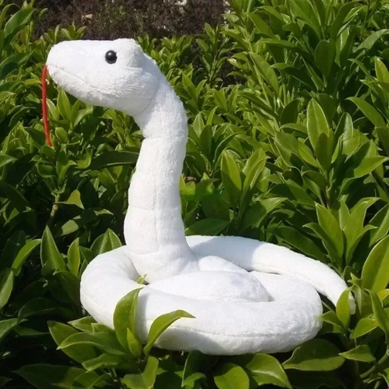 White plush snake toy resting in green foliage, resembling a serpent from Iguro Obanai Cosplay Costume.